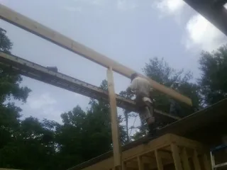 Carpenter setting a ridge beam over a new addition frame — Ice Dam Removal by Roofing Brothers in Guffey