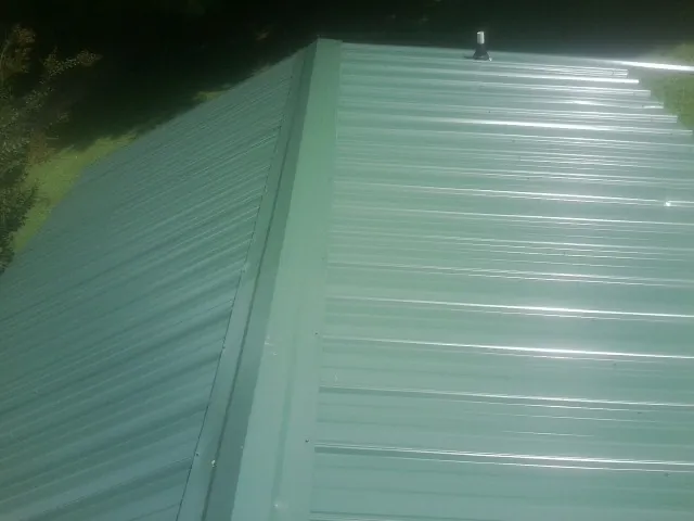New green metal panels meeting at the ridge of a roof — Flat Roof Repair work by our crew in Guffey