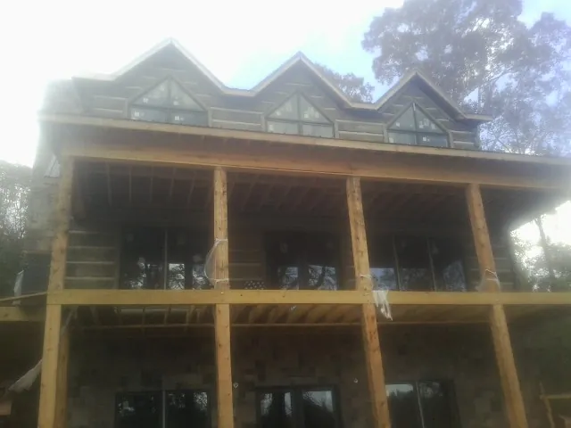Dormers and porch framing on a large log home under construction — Roof Coating work by our crew in Guffey