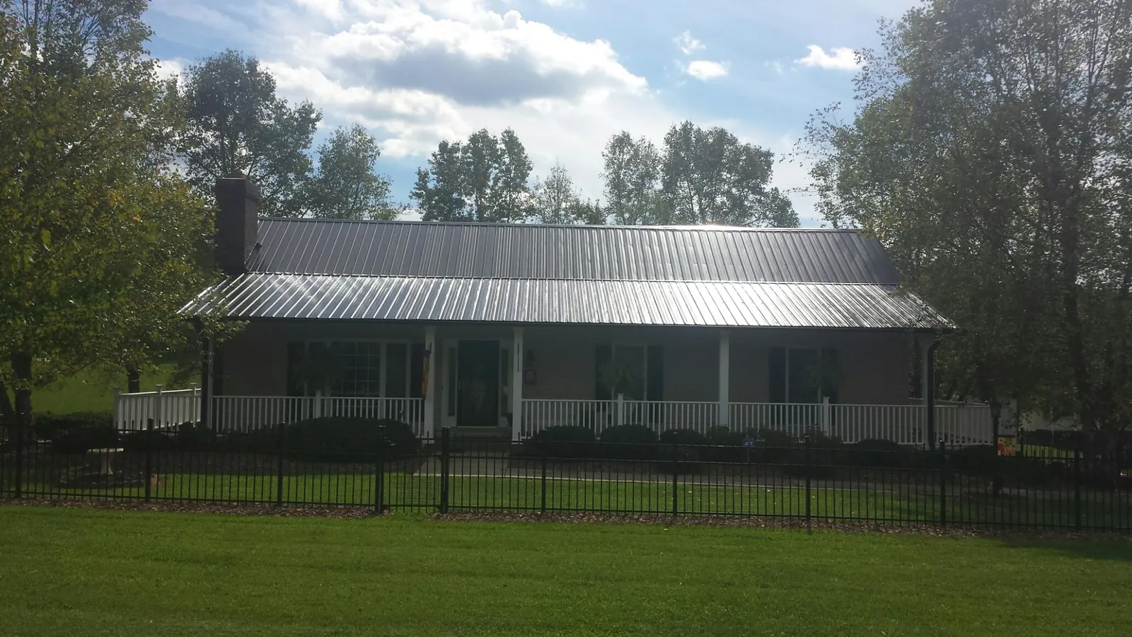 Gray metal roof on a brick ranch with a full width front porch — Gutter Guard Installation work by our crew in Guffey