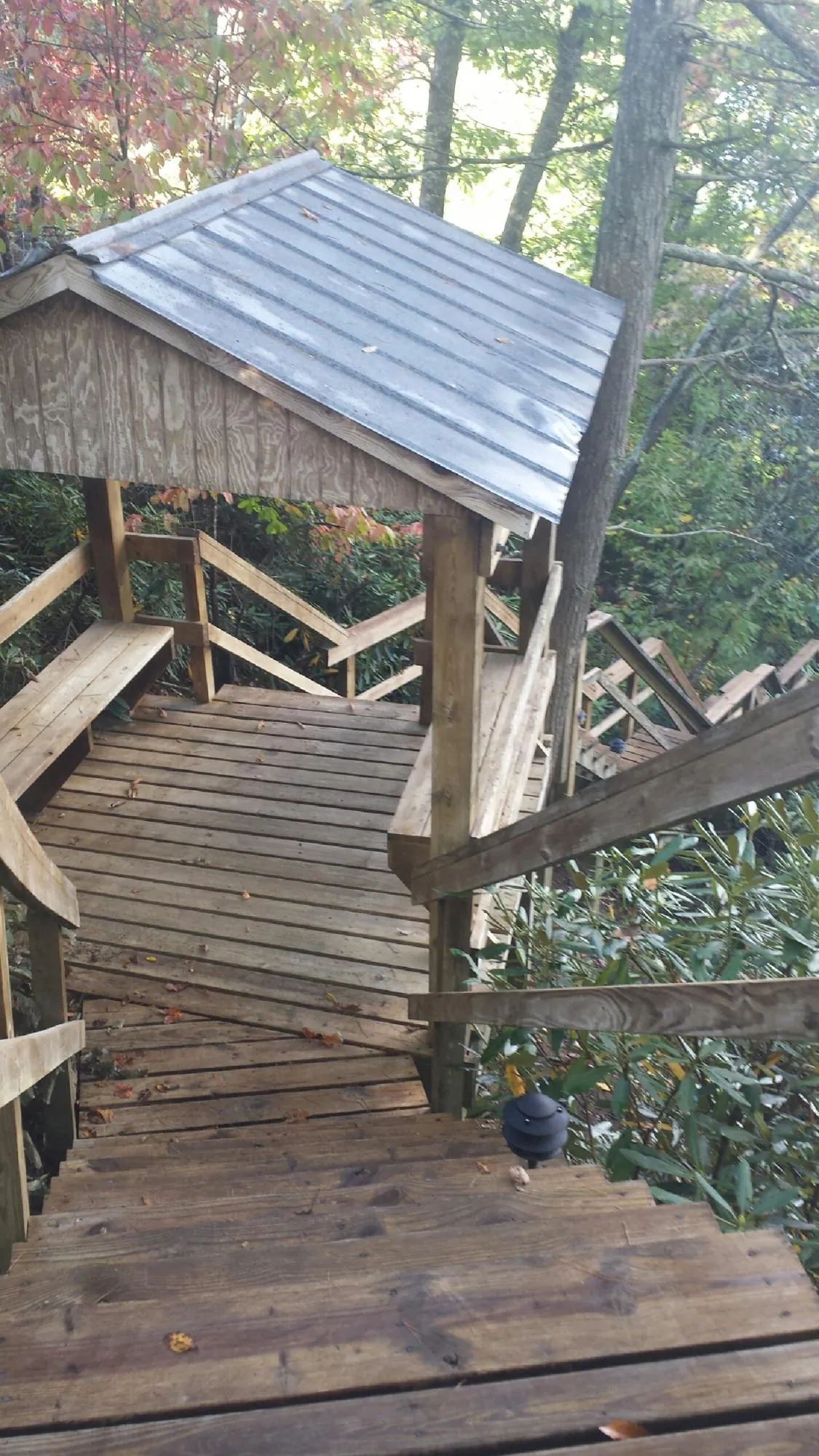Metal roofed shelter over wooden steps on a wooded walkway — Skylight Repair & Installation work by our crew in Guffey