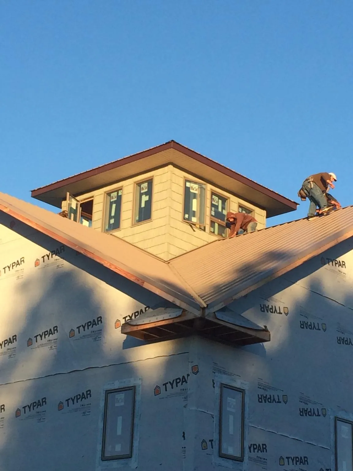 Roofers working around a rooftop cupola on a new metal roof at sunset — Roof Waterproofing in Guffey by Roofing Brothers